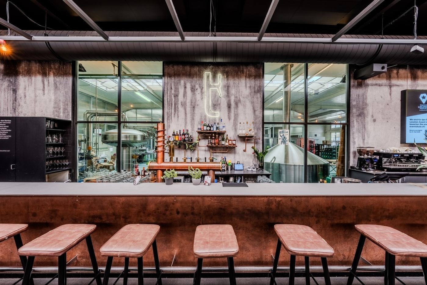 Die Bar mit Hockern und Blick in die Brauerei