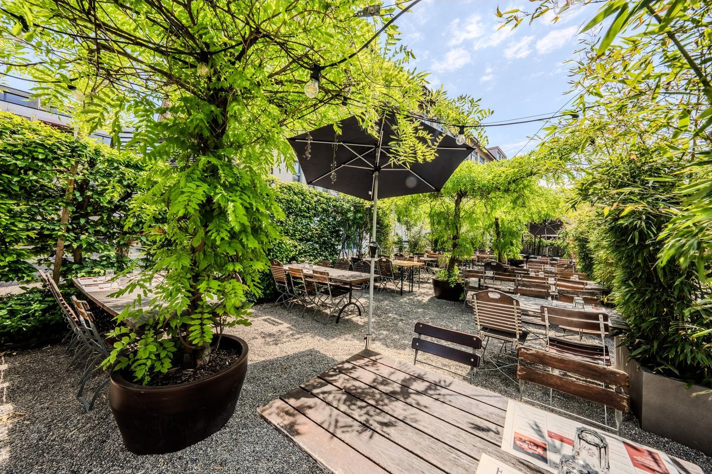 Der Turbinengarten unter Bäumen mit Biertischen