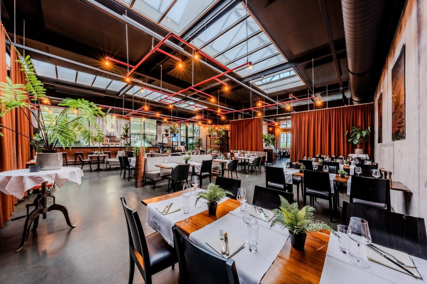 Restaurant Turbinenbräu mit gedeckten Tischen, Pflanzen und Blick in die Brauerei